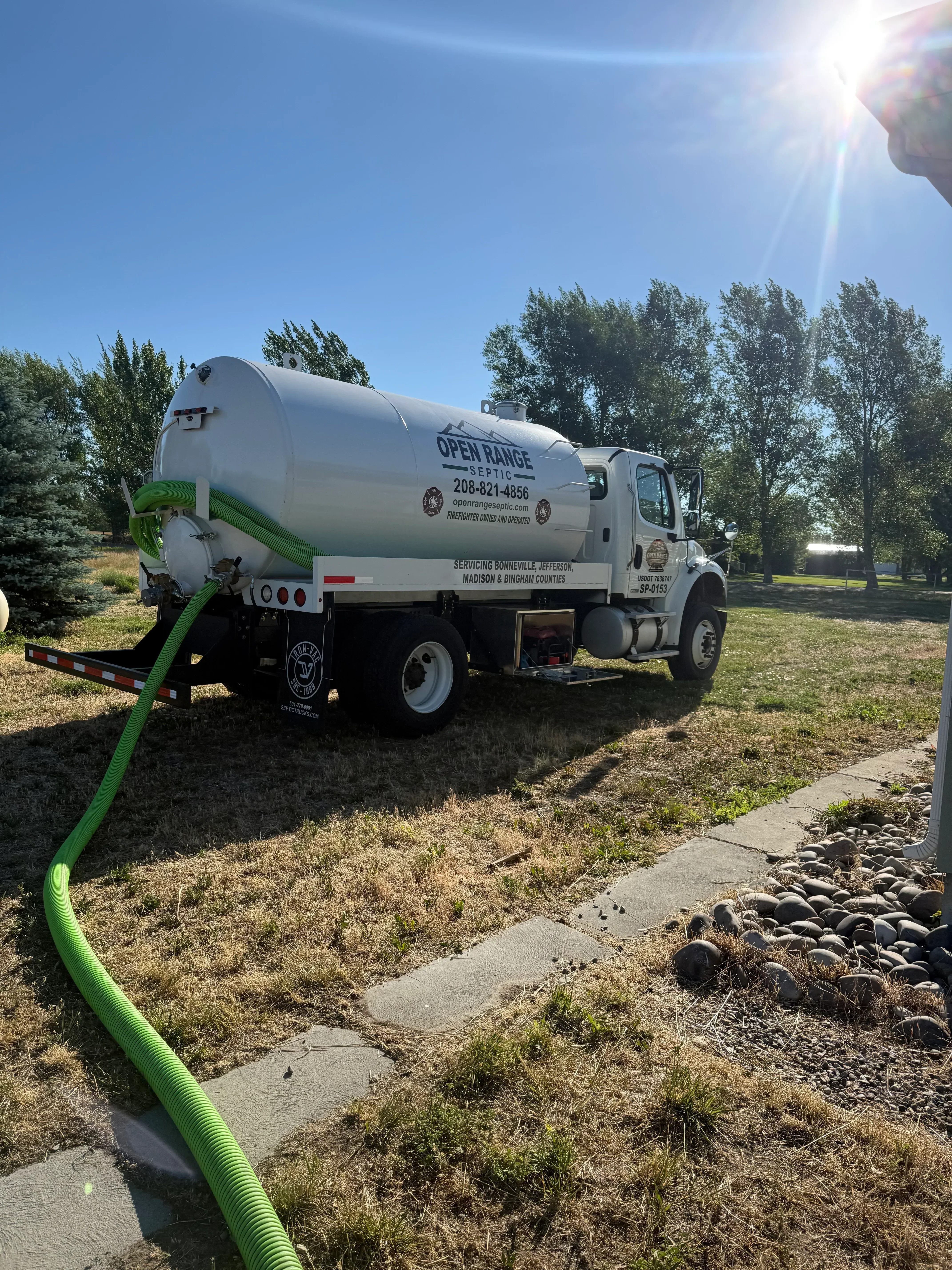 Septic pump truck with green hose connection at residential property