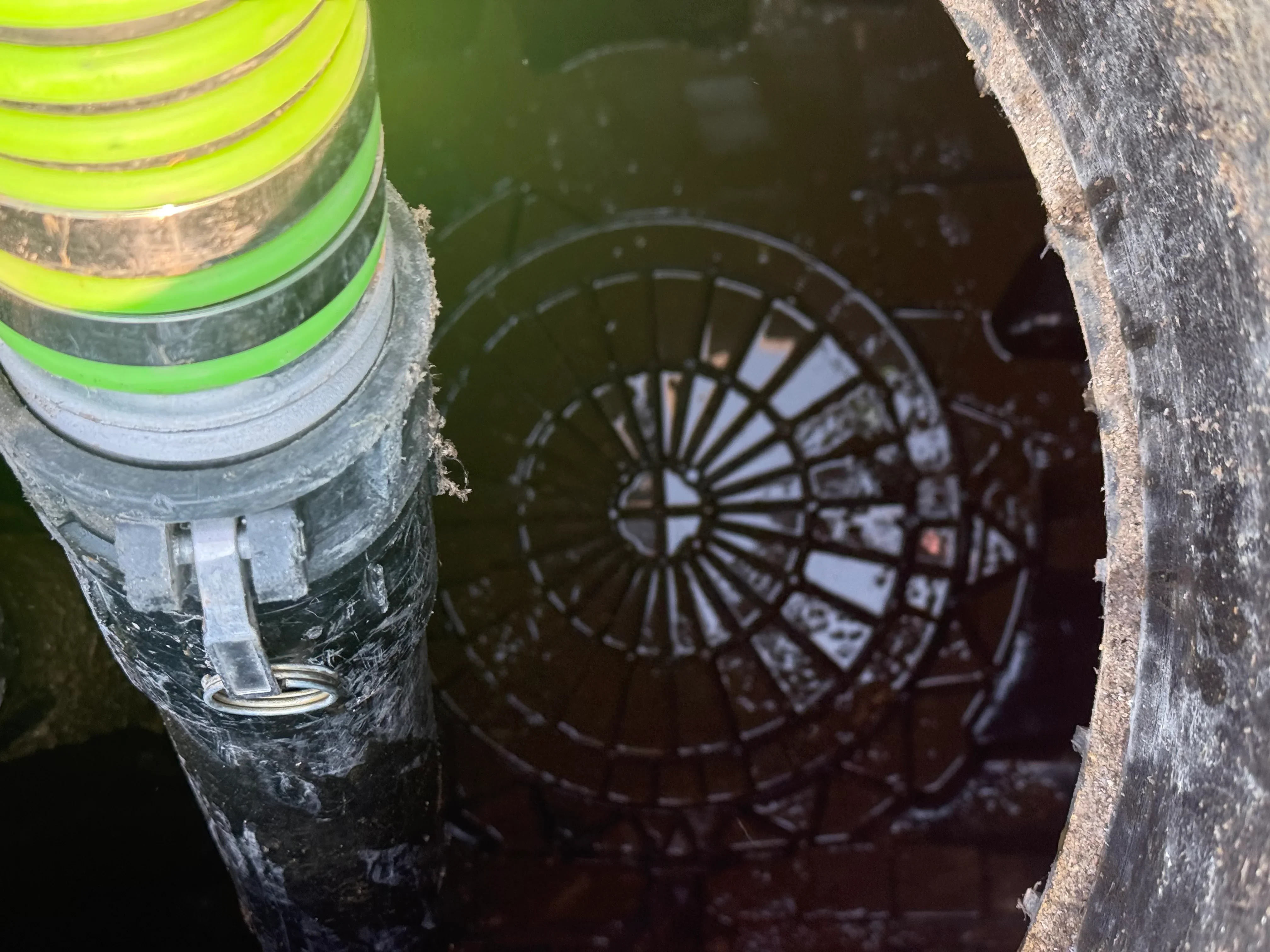 Septic tank access port with concrete structure, metal bands, and safety markers in excavated pit